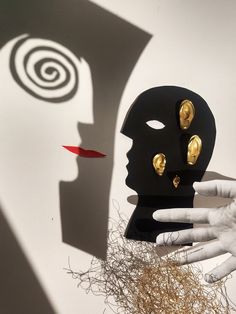 a person's hand is next to a black mask with gold studs on it