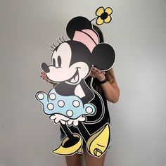 a woman holding up a cut out of mickey mouse