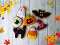 decorated halloween cookies on a white wooden surface with fall leaves and pumpkins in the background