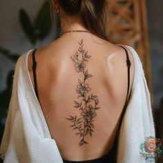 the back of a woman's neck with flowers and leaves tattoo on her left shoulder