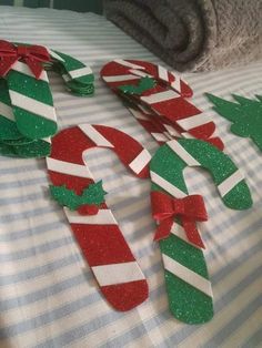 some candy canes are laying on a bed with christmas decorations in the shape of letters