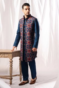 Navy blue long open bundi featuring patola pattern all over. Paired with a solid kurta and pant. - Aza Fashions Traditional Long Sleeve Outerwear With Cutdana, Traditional Blue Nehru Jacket With Traditional Drape, Blue Traditional Wear For Winter, Traditional Blue Bandhgala For Winter, Traditional Blue Wear For Winter, Blue Traditional Nehru Jacket, Transitional Blue Cutdana Bandhgala, Ceremonial Blue Embroidered Nehru Jacket, Blue Traditional Wear For Winter Festivals