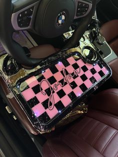 a pink and black checkered tray sitting on the front seat of a car next to a steering wheel