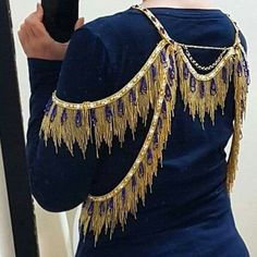 a woman taking a selfie in front of a mirror wearing a blue dress with gold chains on it