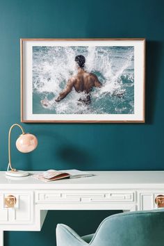 a man swimming in the ocean with his back turned to the camera, framed above a desk