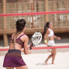 two women are playing volleyball on the beach