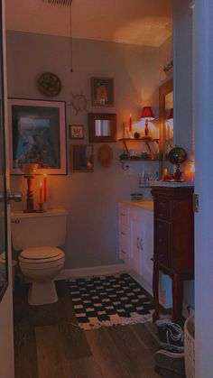 a white toilet sitting in a bathroom next to a wooden cabinet and vanity with candles on it