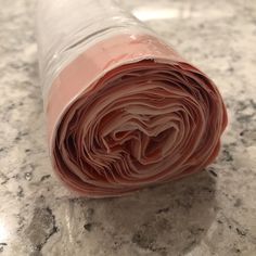 a rolled up piece of food sitting on top of a marble countertop next to a roll of paper