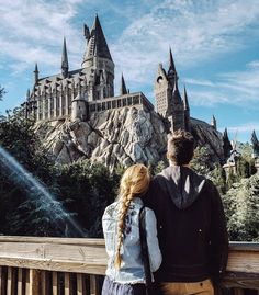 two people standing on a bridge looking at hogwarts castle