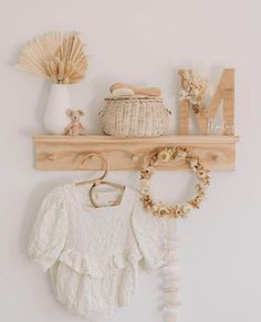 there is a wooden shelf with some items on it and a baby's clothes hanging from it