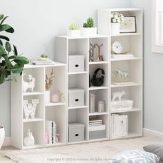 a white bookcase filled with lots of books next to a potted plant