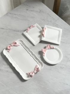 white and pink dishes with bows on them sitting on a marble countertop in a kitchen