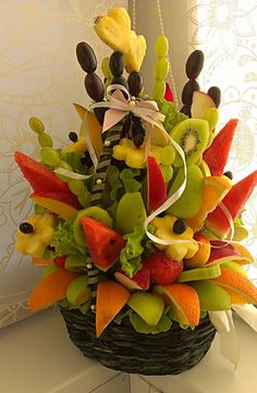 a basket filled with lots of different types of fruit on top of a counter next to a window