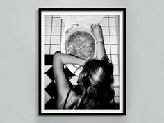 a black and white photo of a woman sitting on a toilet with her hands in the bowl