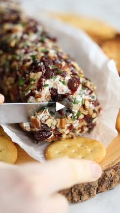 someone cutting up food with a knife on top of some crackers and cheesesticks