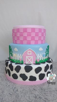 three tiered cake decorated with pink, blue and black farm animals on the side