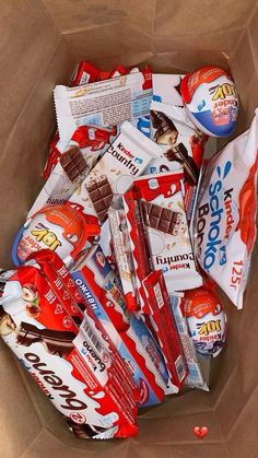 an open box filled with candy bars and candies on top of brown wrapping paper