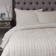 the bed is made with white linens and pillows, along with a silver nightstand