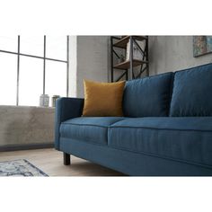 a blue couch sitting in front of a window with a rug on the floor next to it