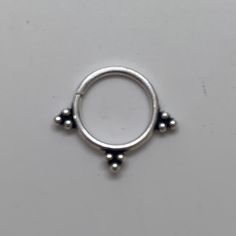 a silver ring with three balls on the outside and one ball at the top, sitting on a white surface