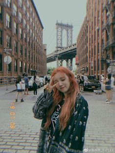 a girl with red hair is standing in the street