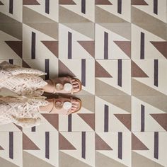 a woman standing on top of a tiled floor next to a white and brown wall