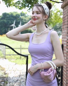 a woman in a purple dress is posing with her hand on her cheek and wearing a white headband