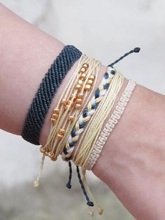 a woman's arm with three different bracelets on it, one is black and the other is gold