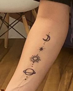 a woman's arm with the sun and planets tattoo on her left leg, next to a white chair