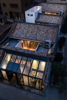 an aerial view of the roof of a building at night with lights on and windows lit up