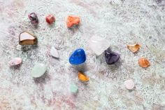 several different colored rocks and stones on a table with white paint splattered over them