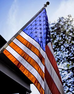 an american flag hanging from the side of a building with blue sky in the background