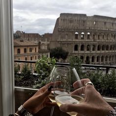 a person holding a wine glass in front of an old building