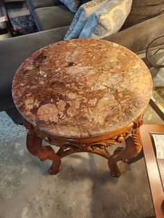 a marble topped table sitting on top of a floor next to a couch in a living room