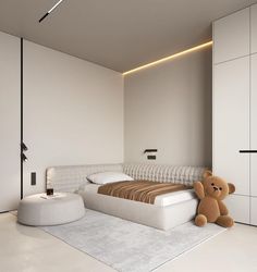 a teddy bear is sitting on the floor next to a bed in a white room