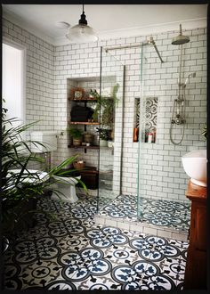 a bathroom with white and blue tiles on the floor, shower, toilet and sink