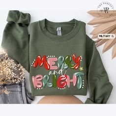 Elevate the Holidays with Our 'Merry & Bright' Women's Sweatshirt . Get ready to make this holiday season memorable with our cute 'Merry & Bright' Women's Sweatshirt. Designed to spread joy and warmth, it's the perfect unique Christmas gift for the special women in your life or for yourself, perfect for a holiday party! Order today to spread holiday cheer and warm the hearts of your loved ones. KEY PRODUCT These Unisex Gildan 18000 sweatshirts are soft and comfortable. The collar is ribbed knit, Christmas Green Sweatshirt With Graphic Print, Christmas Green Graphic Print Sweatshirt, Green Christmas Sweatshirt With Letter Print, Green Christmas Crew Neck Sweatshirt, Christmas Sweater With Letter Print, Christmas Sweaters For Women, Merry Bright Christmas, Unique Christmas Gifts, Christmas Sweatshirts