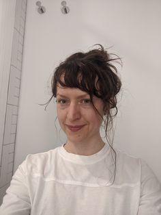 a woman is taking a selfie in front of a mirror with her hair pulled back