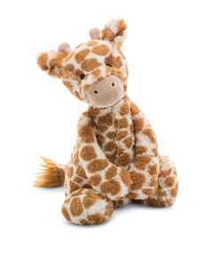 a stuffed giraffe sitting on the ground with it's head turned to the side