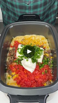 a person standing in front of a food container filled with vegetables and other foods on top of it