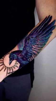 a person with a tattoo on their arm holding a bird in the air and sun behind it