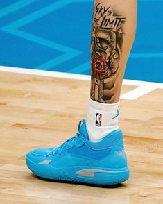 a basketball player's leg with tattoos on it and his shoes in the air