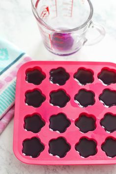 an ice tray with chocolates in it and a measuring cup next to it on a table