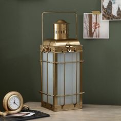 an antique brass lantern on a table with a clock in the corner next to it