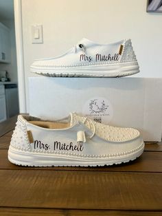 two pairs of white shoes sitting on top of a wooden table next to each other