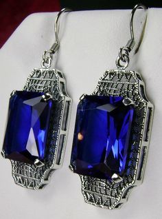 "Simulated Blue Sapphire Earrings Lantern Design#E13 Custom Made Inspired by the Art Deco movement of the early 1900s, these lovely antique reproduction earrings have been crafted in sterling silver. These earrings were refashioned from an antique Art Deco brooch. Each stunning 9 carat simulated blue sapphire gem is 15mm x 12mm. The earrings are 1-3/4\" long and 9/16\" at their widest point. Art Deco style is amazing. The geometric shapes accent the bright facets in the gemstone. These earrings Blue Rectangular Jewelry For Party, Blue Art Deco Drop Earrings, Classic Rectangular Party Earrings, Blue Art Deco Wedding Earrings, Classic Blue Jewelry For Evening, Retro Blue Drop Earrings Jewelry, Vintage Blue Drop Earrings Jewelry, Vintage Rectangular Formal Earrings, Blue Art Deco Jewelry For Evening