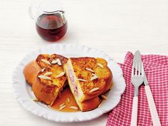 a white plate topped with french toast sandwiches next to a cup of tea and silverware