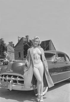 a woman standing next to an old fashioned car