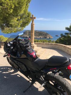 a motorcycle parked on the side of a road next to some trees and water in the background