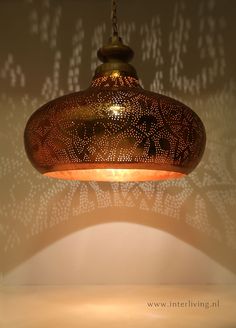 a lamp hanging from the ceiling in front of a wall with writing on it,